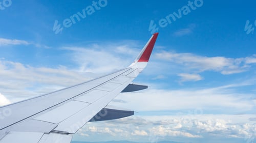 Preview: Airplane wing flying above the sky with white clouds. View from aircraft window.
