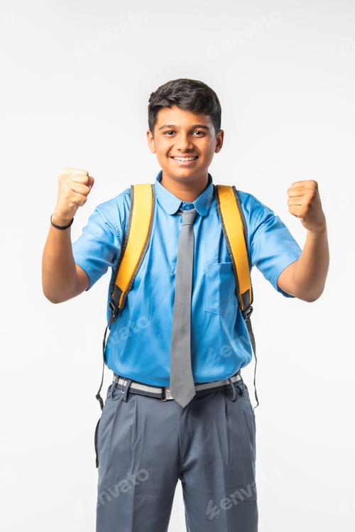 Preview: Indian Asian school boy in uniform with giving thumbs up, celebrating success or pointing to blank