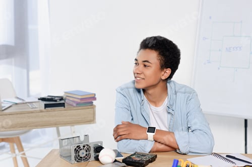 Preview: african american teenager sitting at table with technical equipment at home