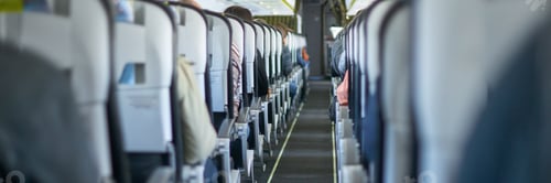 Preview: Interior view of airplane cabin filled with seated passengers and narrow aisle