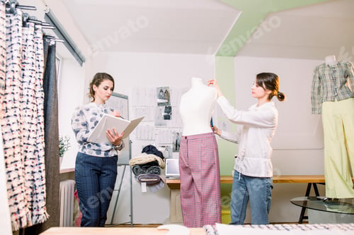 Preview: Portrait of two young women fashion designers or tailors, measuring mannequin