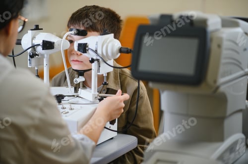 Preview: Ophthalmologist examining boy's vision with modern equipment in clinic