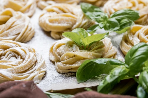 Preview: Pasta alluovo, Tagliatelle or fettuccine. Round balls of raw pasta on the wooden cutting board
