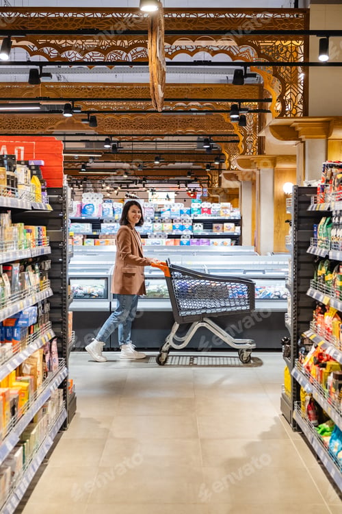 Preview: a woman with a cart walks between rows of shelves in a grocery store