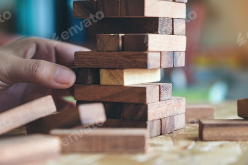 Preview: Closeup image of a hand holding and playing Tumble tower wooden block game