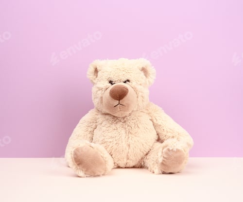 Preview: Cute beige teddy bear sitting on purple background