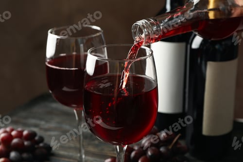 Preview: Wine is poured from a bottle in glass on wooden table, close up