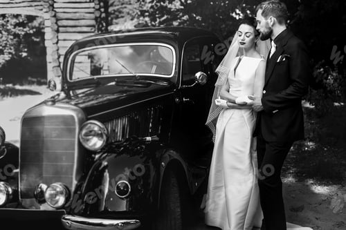 Preview: Wedding couple holding hands on background of stylish black car