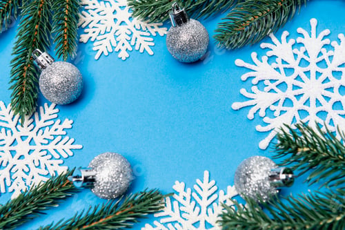 Preview: top view of snowflakes, silver baubles and spruce on blue background