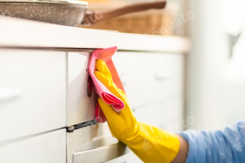 Preview: Smiling young woman cleaning oven at kitchen