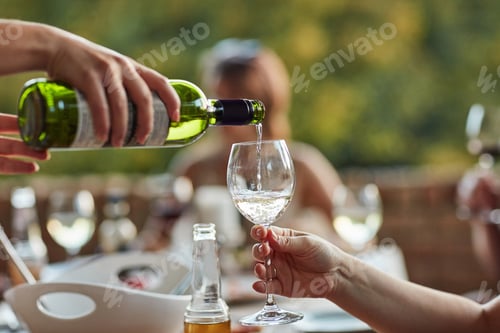 Preview: Shot of an unidentifiable young man pouring wine in his friends glass at a backyard dinner party