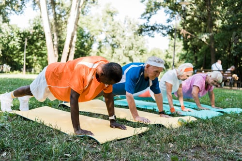 Preview: selective focus of african american man doing plank exercise with pensioners on fitness mats