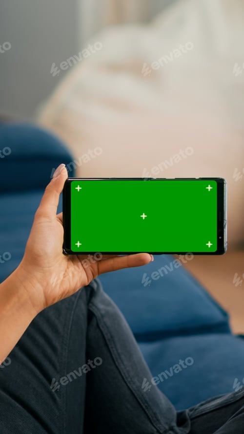 Preview: Close up of woman holding smartphone with mock up green screen chroma key display