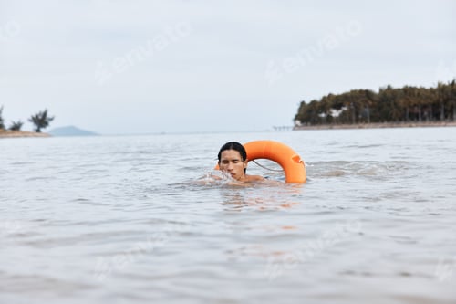 Preview: Watchful Lifeguard on a Summer Beach: Asian Man Rescuing with a Lifebuoy