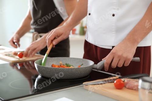 Preview: Male chef cooking vegetables on electric stove, closeup