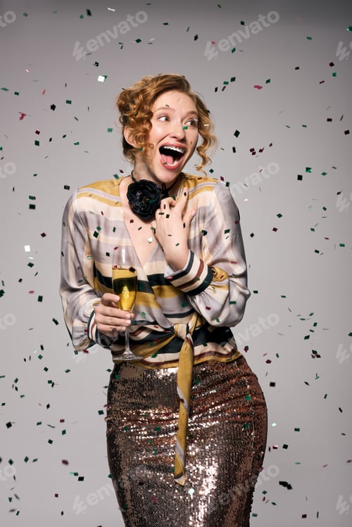Preview: Young woman joyfully celebrating with a drink while confetti falls around her
