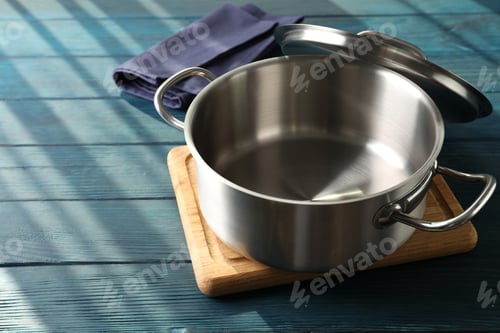 Preview: Empty metal pot on cutting board on wooden table