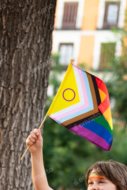 Preview: Child waving intersex-inclusive progress pride flag at pride parade