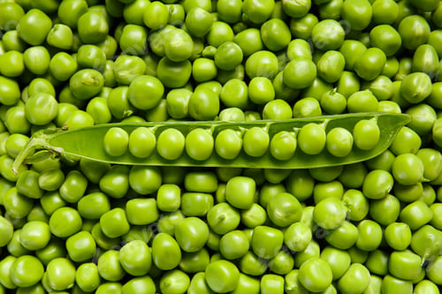 Preview: An open pod of fresh green peas lies on pea grains, top view. Background of sweet green peas.