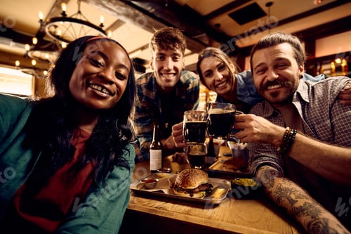 Preview: Multiracial group of happy friends taking selfie while gathering in a bar.