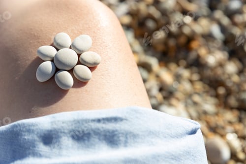 Preview: Pebbles arranged in flower shape on girls leg
