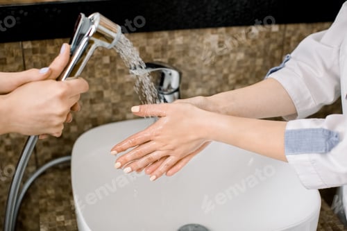 Preview: Close up of hands of female doctor cosmetologist, wearing white medical uniform, washing and rinsing