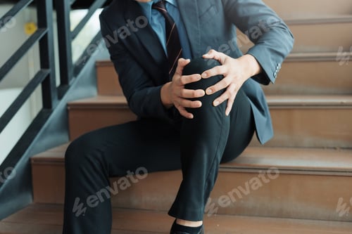 Preview: Businessman experiencing knee pain injury on stairs