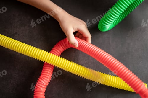 Preview: anti stress sensory pop tube toys in a kids hands. kids hands plays with poptube toy on black table
