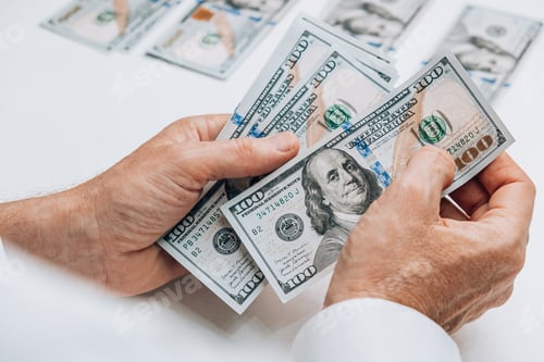 Preview: the man counts cash hundred-dollar bills of the USA and puts them in stacks. employee's salary.