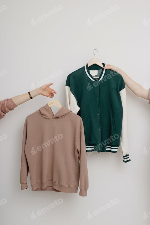 Preview: Two hands holding clothes on hangers.