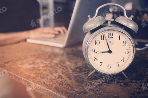 Preview: A business owner using laptop and working on time with clock on the table