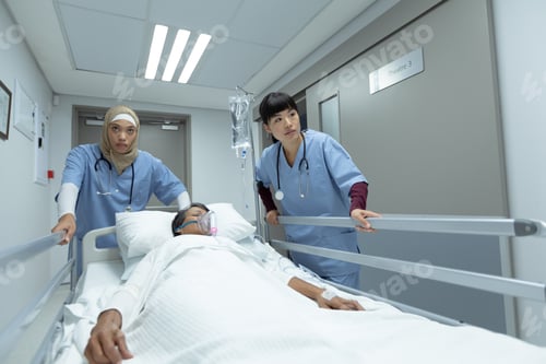 Preview: Diverse female doctors pushing emergency stretcher bed in corridor at hospital.