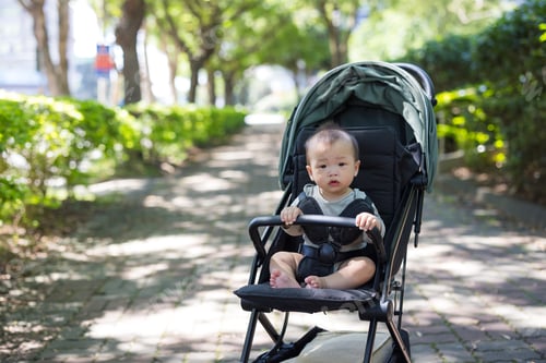 Preview: Cute baby sitting in stroller in city street