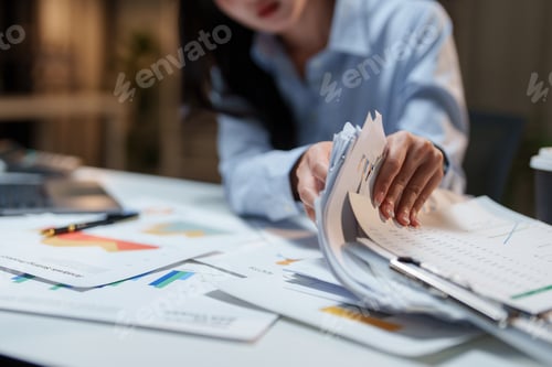 Preview: Woman working late sorting financial business documents