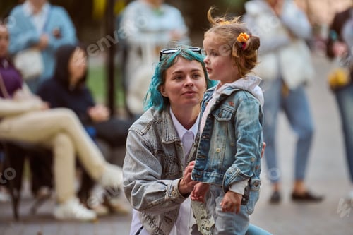 Preview: Woman with blue hair engaging with child in park setting