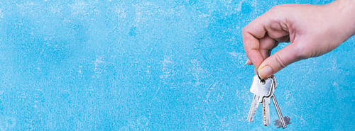 Preview: Female hand holding keys on blue background. Banner
