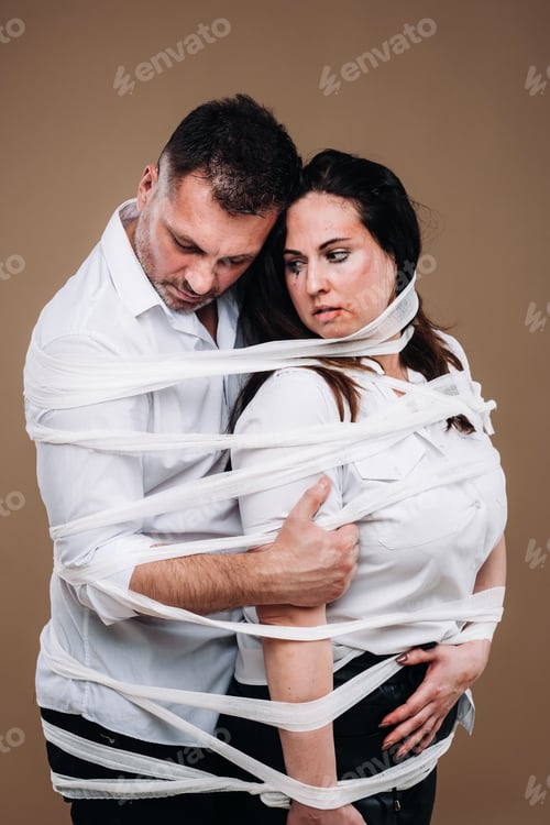 Preview: An aggressive man embraces a battered woman and is wrapped in bandages together. Domestic violence