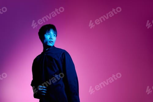 Preview: Confident young man poses against a vibrant purple backdrop, showcasing modern fashion