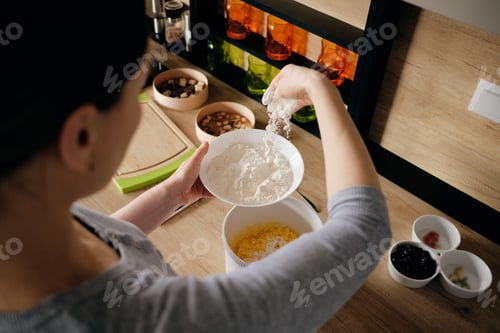 Preview: Woman hand sprinkling flour in a white bowl