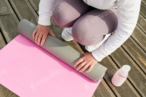 Preview: Woman Rolling Up a Pink Yoga Mat