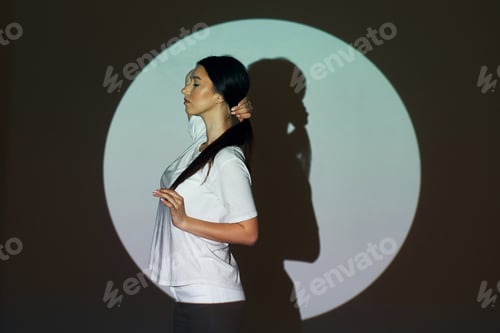 Preview: Circle and shadow. Beautiful young woman is in projector neon lights in the studio