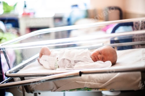 Preview: Close up of a newborn baby laying oh a bed in neonatal department of a hospital