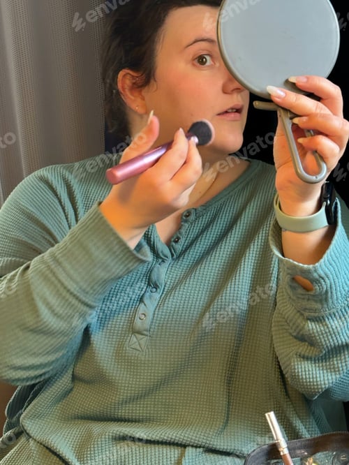 Preview: Young millennial woman applies makeup cosmetics to her face in preparation to go out on the town