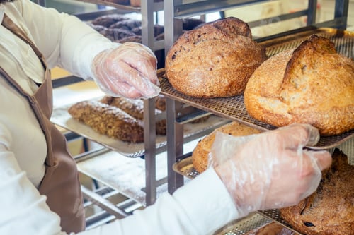 Preview: Cheerful baker delivering bread to client in store