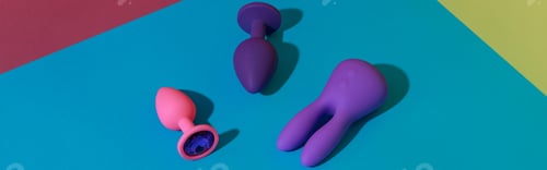 Preview: Top view of buttplugs and dildos vibrator for sex on colored background. Sex shop concept