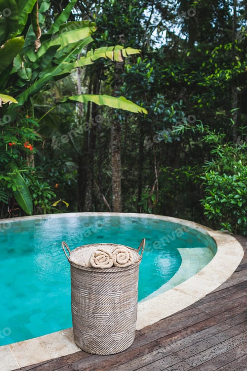 Preview: Two beige rolled towels in wicker basket near private pool with turquoise clear water