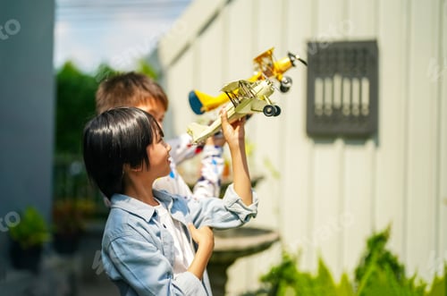 Preview: Happy lovely boys having fun outdoors, playing with airplane toy and smiling joyfully in park on a l