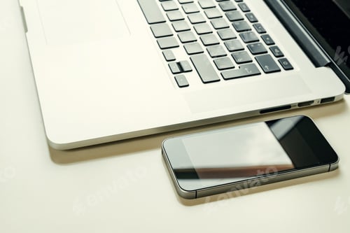 Preview: Close up of black smartphone near open laptop