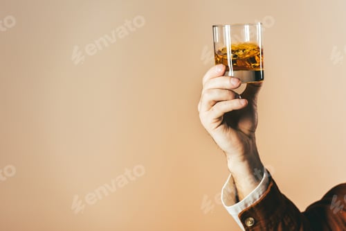 Preview: cropped shot of man holding glass of whiskey isolated on beige