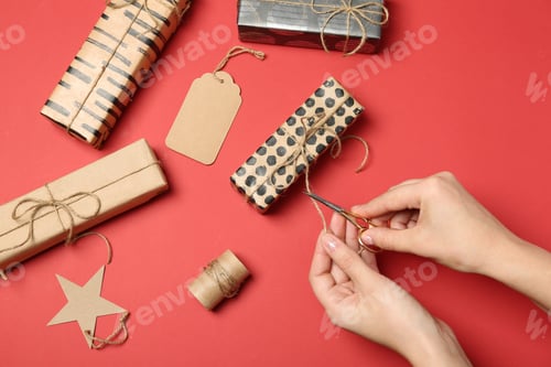 Preview: Woman decorating gift box on color background, top view